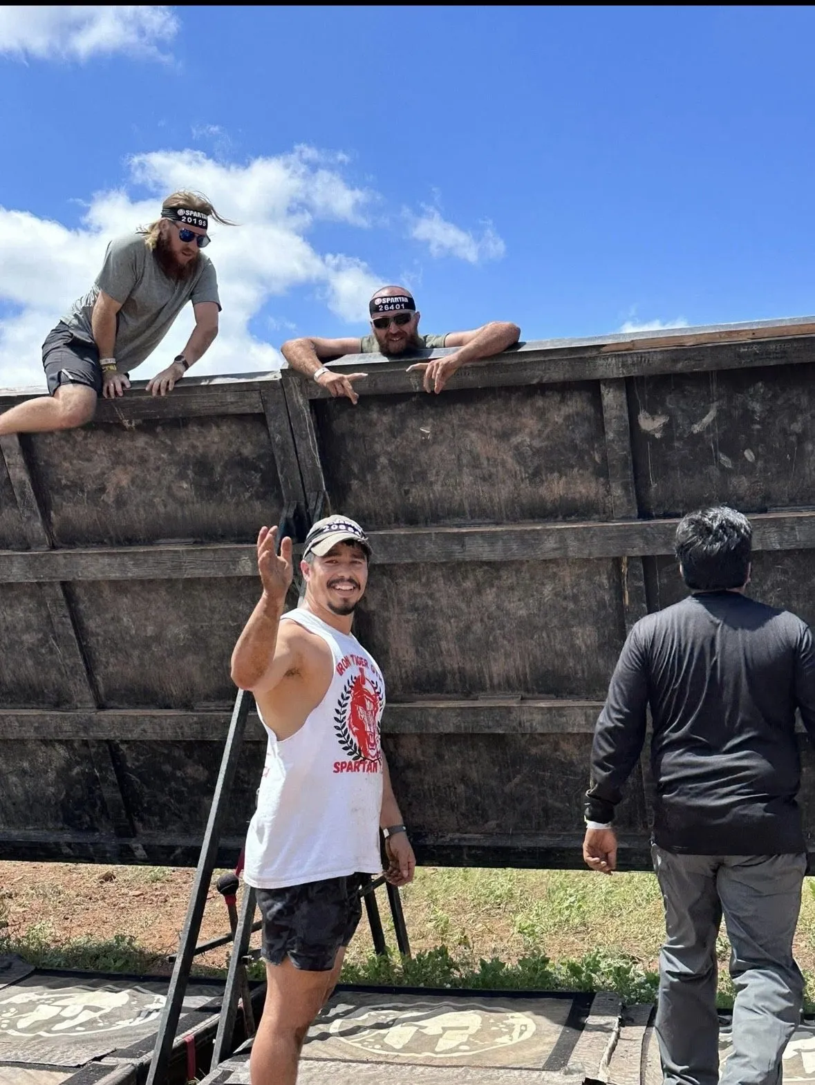 Iron Tiger members helping each other over an obstacle wall